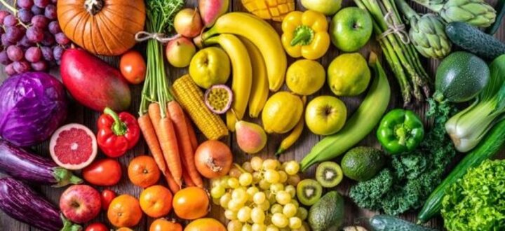 Colorful array of fruits and vegetables arranged on a wooden surface.